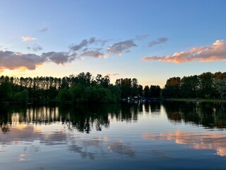purple clouds reflection on the lake surface, trees silhouettes reflections on the water surface, twilights lake in the park, natural colors, very calm and peaceful