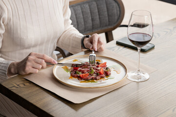 Woman eating dish of fresh tomatoes, greens and meat. Eating out