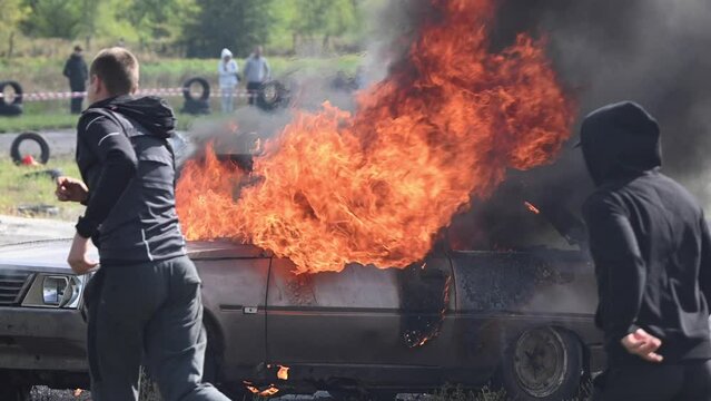 A car is set ablaze as part of a training exercise in Ukraine. The flames are intense, and smoke billows into the sky