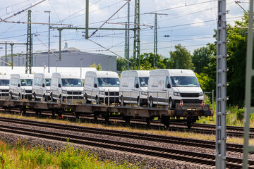 Naklejka premium Many new modern electric and fuel cars vans transportation by cargo freight train railway wagon. Railroad export and import automotive logistics service. Safety and insurance goods shipping industry
