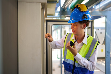 Engineer or worker working at machine control panel and checking pipeline valves or water tank area at urban industrial site