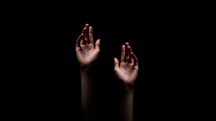 Two hands reaching up towards the dark, unknown, or possibly a source of light, suggesting a sense...
