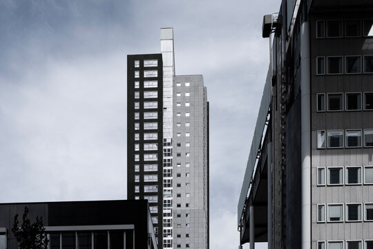 A tall grey office building standing under a cloudy sky, highlighting its towering presence and modern architectural style in an urban setting in Rotterdam