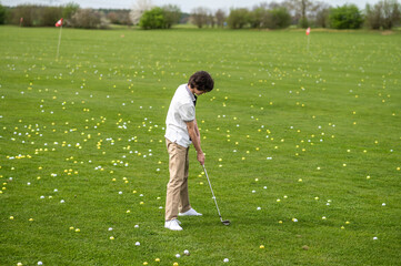 Fototapeta premium Dark-haired young guy training in a golf club
