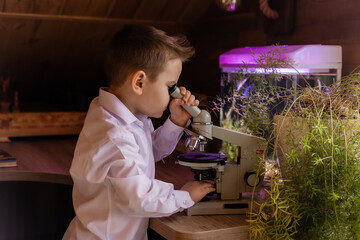 little boy is working with a microscope at home