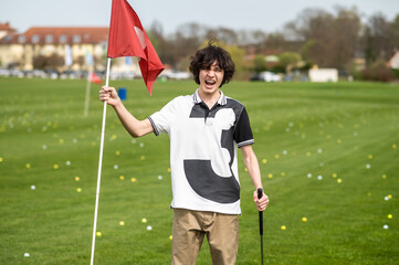 Young golfer with golf flag looking excited