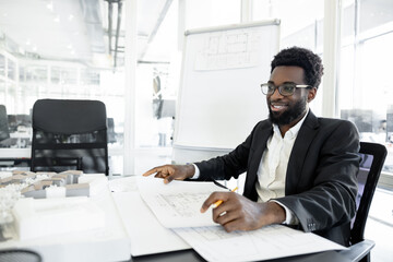 Smiling and successful dark-skinned businessman in his office