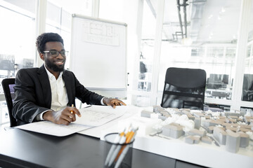 Smiling and successful dark-skinned businessman in his office