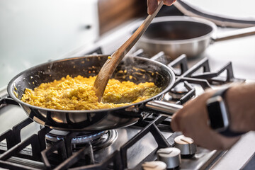 Preparation of saffron risotto in a pan on a gas stove