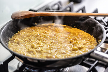 Preparation of saffron risotto in a pan on a gas stove