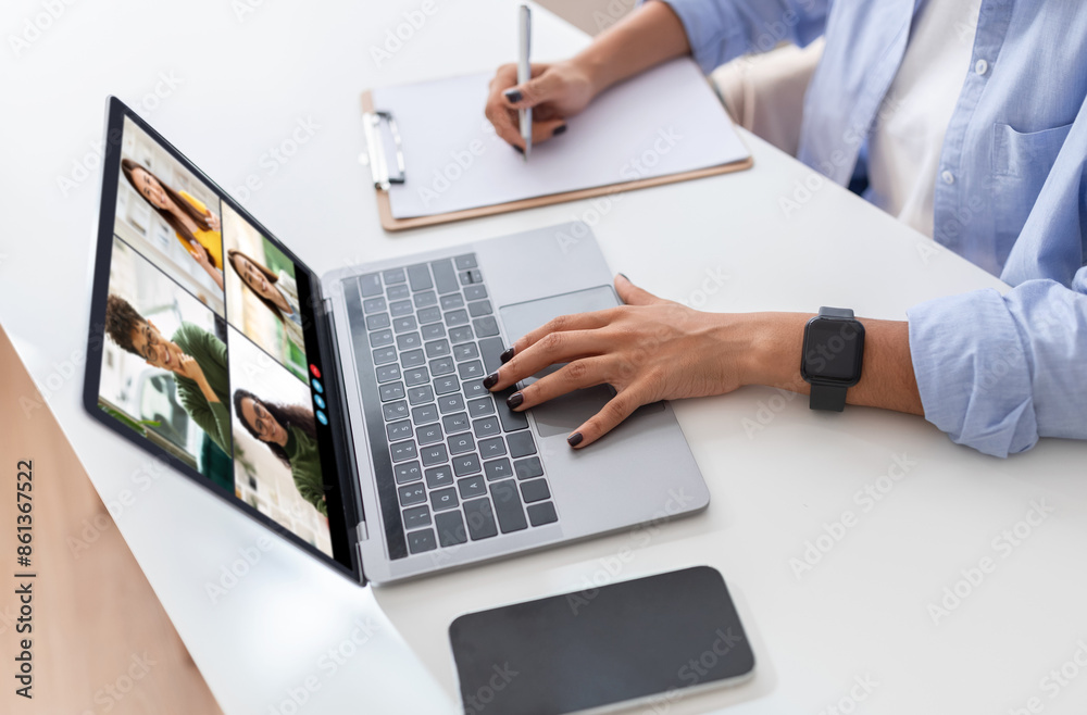 Poster a woman is seated at a white desk with a laptop in front of her. she is using one hand to navigate t