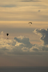 Paragliders gliding in the backlight in Ölüdeniz with the light filtering through the clouds