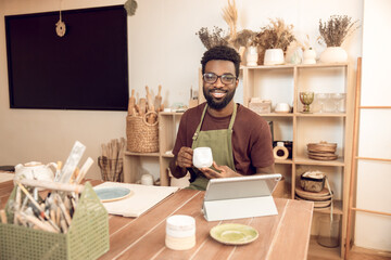 Dark-skinned sculptor demonstrating a new cup to the audience on online tutorial