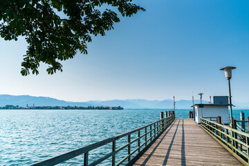 Germany, Landing stage for boats and ferry at lindau lindenhofpark public park with view to old town lindau island houses in summer with blue sky