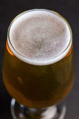 light golden beer in a glass glass on a black background