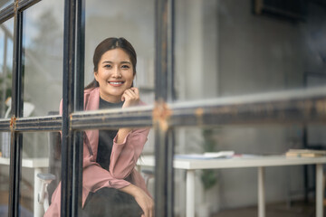 A woman is sitting in front of a window with a smile on her face