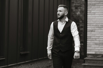 A man in a suit and vest walks down a sidewalk. He is smiling and he is in a good mood