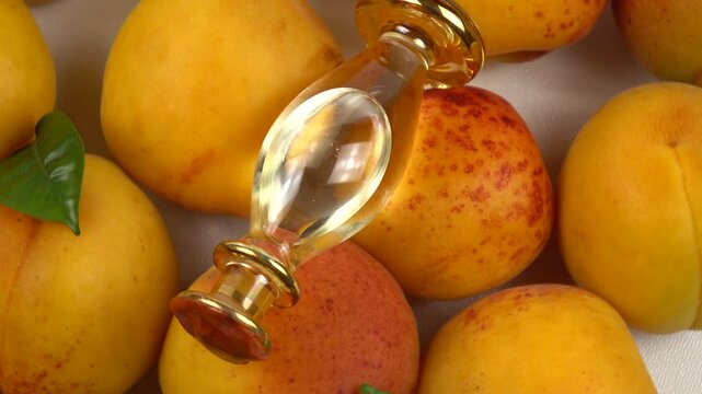Glass bottle with apricot kernel oil placed on the ripe fresh apricot fruits, background