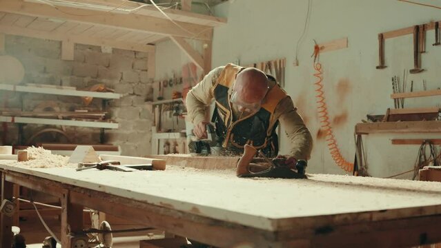 Wood, sander and carpenter in workshop with tools for furniture, production or construction project. Handyman, building and woodworking process in warehouse with manufacturing or labor in business
