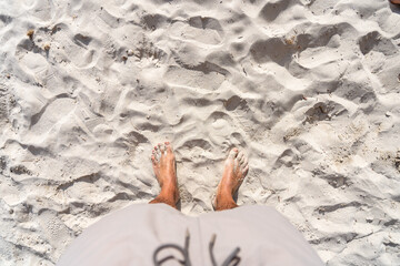 Man's feet on white sand