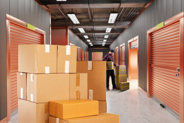 Storage in warehouse cell. Boxes and man near safekeeping cameras. Rent self storage unit. Guy...