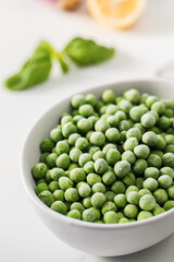 A bowl of frozen green peas on a white background. Fresh and healthy vegetable