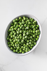 A bowl of frozen green peas on a white background. Fresh and healthy vegetable