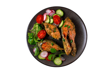 Oven baked pink salmon steaks with vegetable salad on dark plate isolated on white