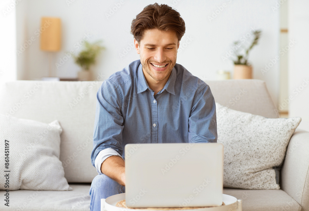 Aufkleber a man sits on a couch and smiles while using a laptop.