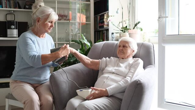 Caregiver measuring blood pressure of en elderly woman at home
