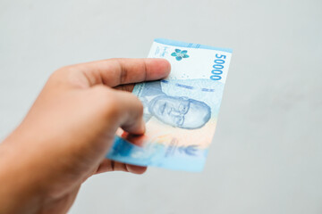 Male hand showing Indonesian rupiah banknotes.