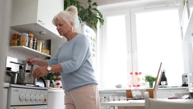 Mature woman preparing tea in her kitchen
