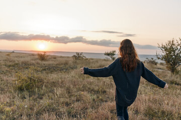 silhouetted woman embracing the sunset in a vast field under the colorful sky