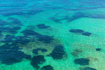 Aerial view of ocean and coral reefs in southern Australia.  Water is dotted with small rocks and bubbles, creating a peaceful and serene atmosphere