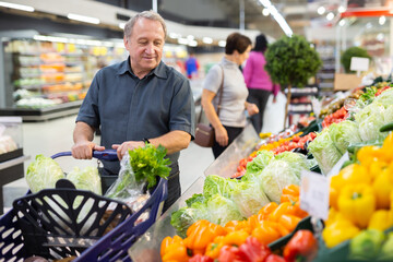 Elderly man chooses china cabbage in vegetable and fruit department