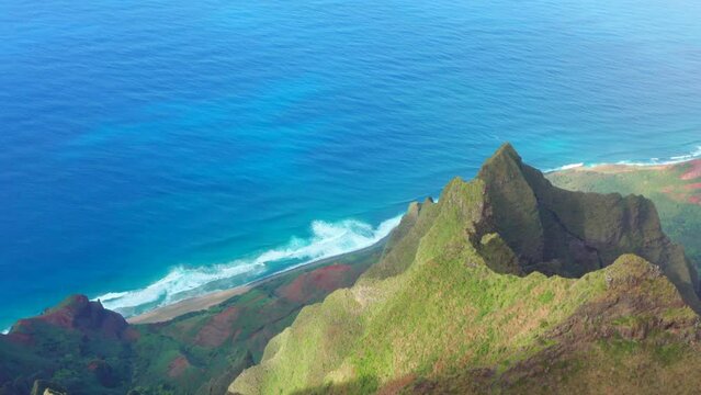 Magnificent Hawaiian nature aerial flying over green jungle mountain peaks revealing tropical beach on Na Pali coast national park. Incredible flying tilt view dramatic mountains blue turquoise ocean