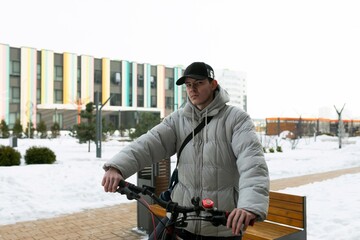 A man in a cap stands with a bicycle in the courtyard of a house