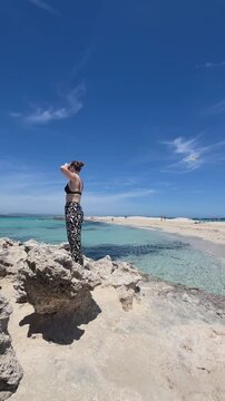 Solo female traveler exploring a wild empty beach in Formentera. Vertical video capturing freedom, adventure, untouched nature and peaceful Mediterranean island travel experience.
