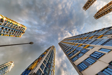 view from below into storm sky with dark clouds of large modern skyscraper residential complex