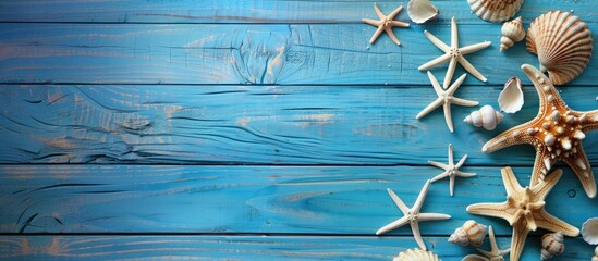 Fototapeta premium A summer beach scene featuring a blue wooden background with starfish and seashells, ideal for adding text or images in the open area. image with copy space