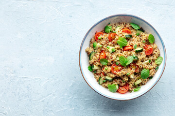 Quinoa tabbouleh salad in a bowl, a healthy dinner with tomatoes and mint, shot from above with a place for text