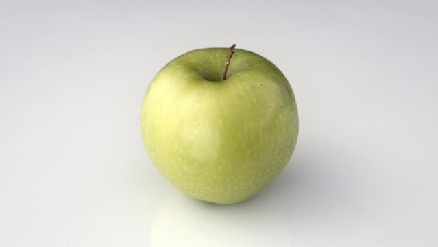 Green apple on white background. Close up of an apple slowly rotating.