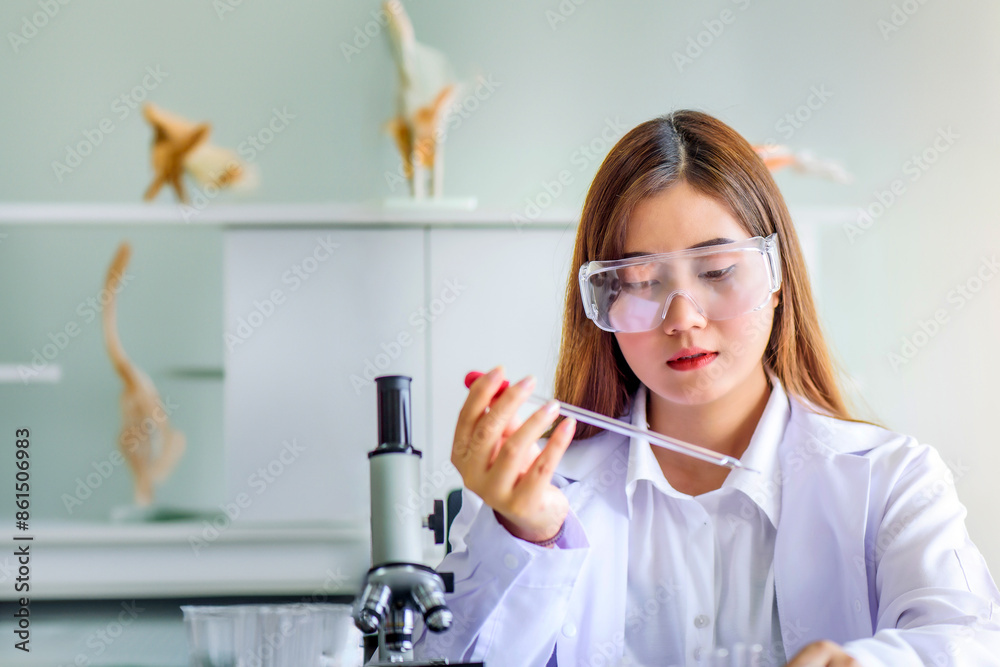 Wall mural attractive young asian scientist woman lab technician assistant analyzing sample in test tube at lab