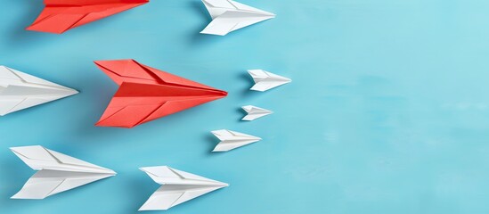 A red paper plane in a group of white ones on a blue background, highlighting leadership concept with empty space for text or image. image with copy space