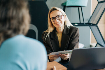 A smiling female consultant advises a client on the choice of color for renovation.