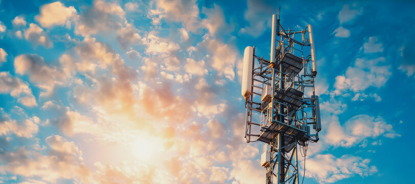 A cellular tower against a sunset sky with fluffy clouds