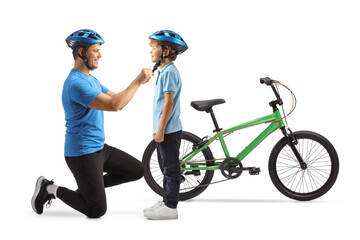 Naklejka premium Man putting on helmet on a boy for a bicycle ride
