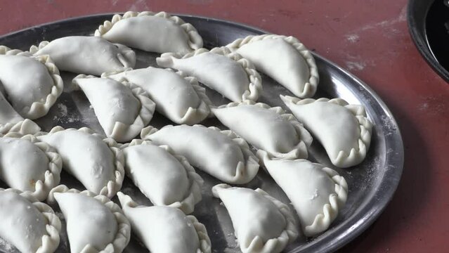 
Raw Argentine empanadas on a platter.  
Creole meat empanadas. Empanadas with traditional repulgue. Typical Argentine food.