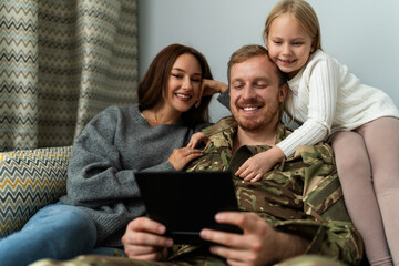 Portrait of military man watching family album with his wife and daughter