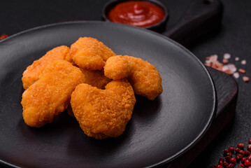 Delicious fresh crispy chicken nuggets on a dark concrete background